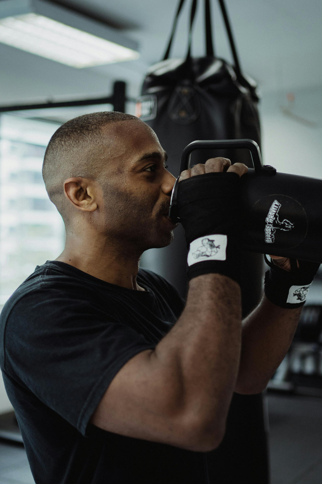 man in black sports wear drink O.R.S hydration water in a boxing gym