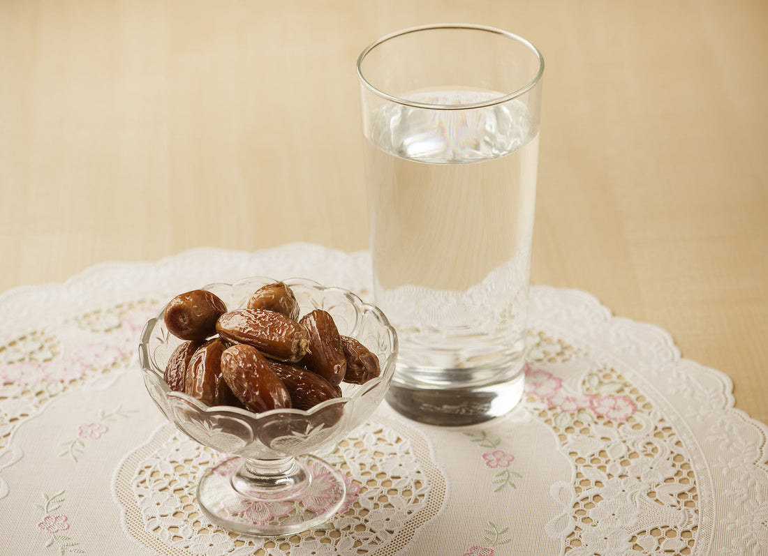 Image of dates and water on a lace placement and wooden table.